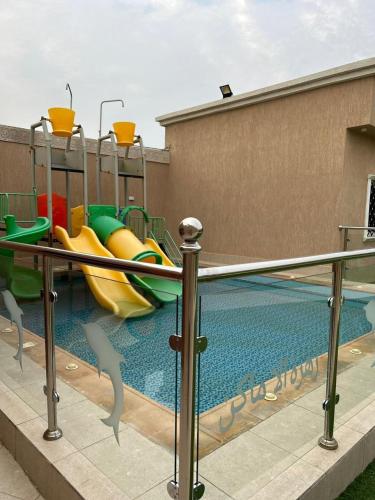 a swimming pool with a slide and a playground at استراحة زهرة الاماكن (1) in Jeddah