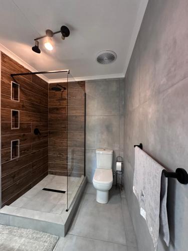a bathroom with a toilet and a glass shower at The White Rose Home in Lobamba
