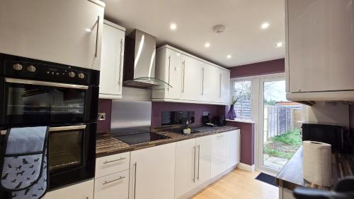 eine Küche mit weißen Schränken und einem großen Fenster in der Unterkunft Palm Trees House - Perfect for Professionals & Families - Long-Term Stay Available in St Ives