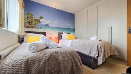 ein Schlafzimmer mit 2 Betten und einem Wandgemälde in der Unterkunft Palm Trees House - Perfect for Professionals & Families - Long-Term Stay Available in St Ives