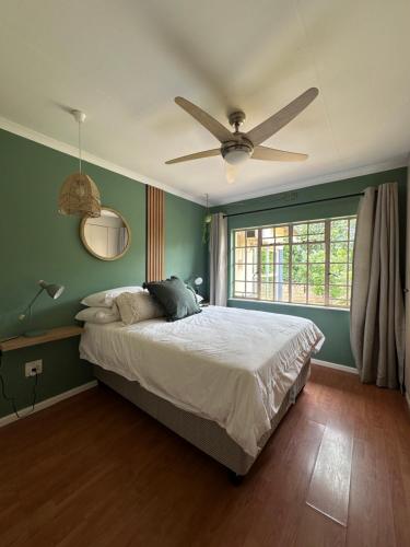 a bedroom with a bed and a ceiling fan at The White Rose Home in Lobamba