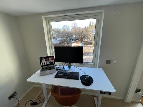a desk with a computer and a laptop and a window at Eget hus anno 2024 Danderyd, 15min till STHLM city in Danderyd