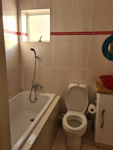 a bathroom with a toilet and a tub and a window at Modern Seaview Apartment in Summerstrand