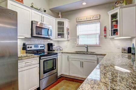 a kitchen with white cabinets and granite counter tops at Crane's Landing at Pirates Bay in Port Aransas