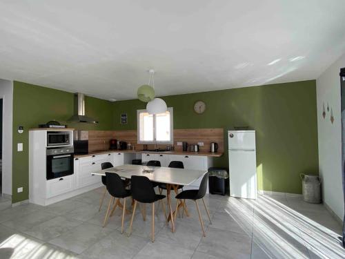 cocina con paredes verdes, mesa y sillas en Au Moryllon en Lompnas