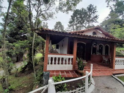 una pequeña casa con una cerca blanca delante de ella en Sítio Nosso Cantinho en Mogi das Cruzes
