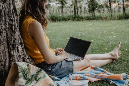 a woman sitting under a tree with a laptop at Feldgärtenhof in Silandro