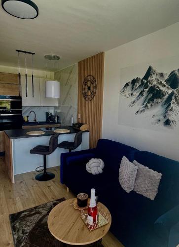 a living room with a blue couch and a kitchen at Apartmán pod Tatrami in Poprad