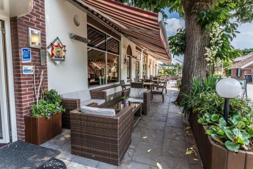 a patio with wicker chairs and tables outside of a restaurant at HCR Prinsen in Haarlo
