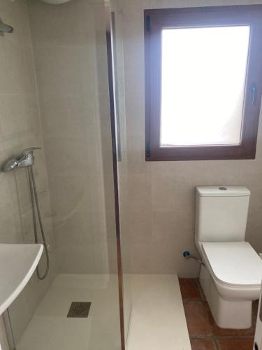 a bathroom with a shower and a toilet and a window at Villa Arriba in Periana