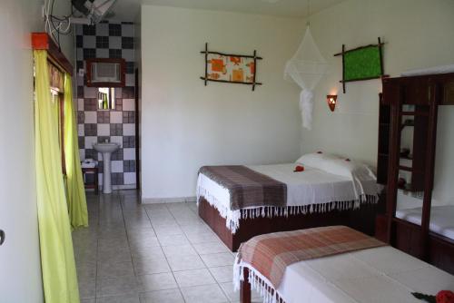 a small room with two beds and a bathroom at Pousada Da Luz Carapibus in Jacumã