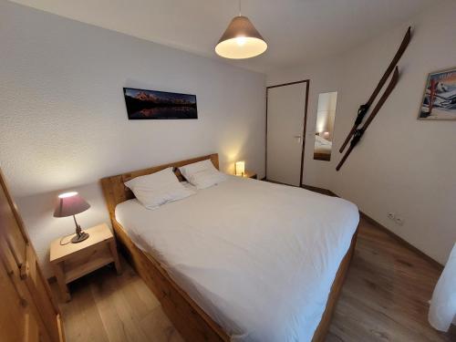 - une chambre avec un lit blanc et une lampe sur une table dans l'établissement Appartement 4 pers rénové, lumineux, au centre des Gets, proche pistes et commerces - FR-1-598-114, aux Gets