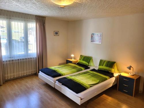 a bedroom with a bed with green sheets and a window at Chalet Lilo 4 Zimmer big View in Beatenberg