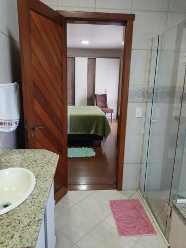 een badkamer met een douche en een slaapkamer met een bed bij Nascer do Sol - Edelweiss in Nova Petrópolis