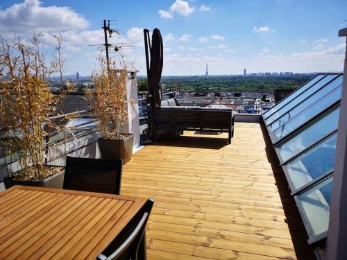 a balcony with a wooden table and bench on a building at Maison Exceptionnelle ! Vue tour Eiffel et Paris in Suresnes
