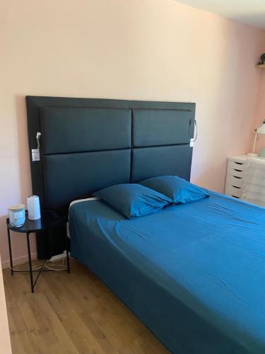 1 dormitorio con cama azul, cabecero y mesa en La chiliere, en Ceyreste