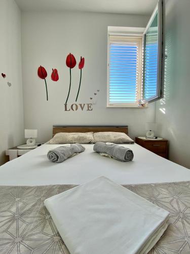 two beds in a bedroom with red flowers on the wall at Apartment Tena in Novalja