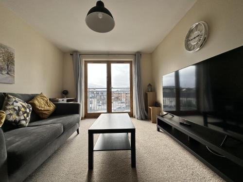 a living room with a couch and a tv and a table at Waterside View Apartment in Inverness
