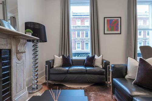 a living room with a leather couch and a fireplace at Beautiful 1 Bed Flat close to Regents Park in London