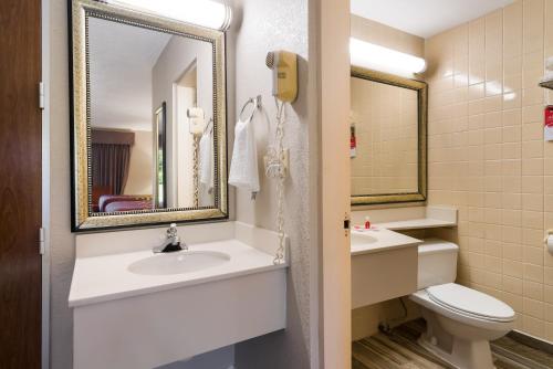 y baño con lavabo, aseo y espejo. en Econo Lodge - Perry National Fair Ground Area, en Perry