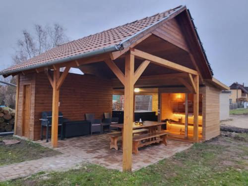 a wooden pavilion with a picnic table and a table at Olivér Apartmanház in Balatonlelle