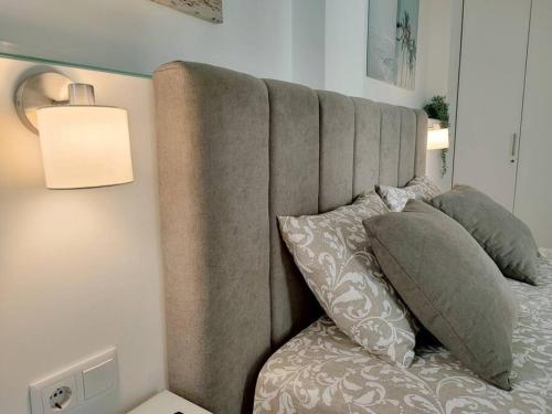 a bed with a gray headboard with pillows and a lamp at Apartamento Mar & Sal in Mindelo