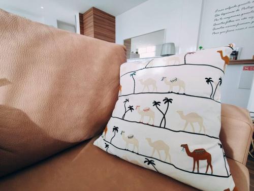 a bed with four pillows with camel and palm trees at Apartamento Mar & Sal in Mindelo