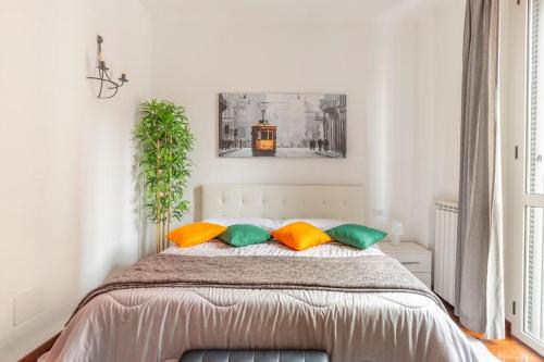 1 dormitorio con 1 cama con almohadas de color naranja y verde en Modern apartment in Milano Centrale next to Metro M5 - Sarca 73, en Milán