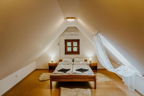 Zimmer im Dachgeschoss mit einem Bett und 2 Teppichen in der Unterkunft Hársfa Vendégház in Hegymagas