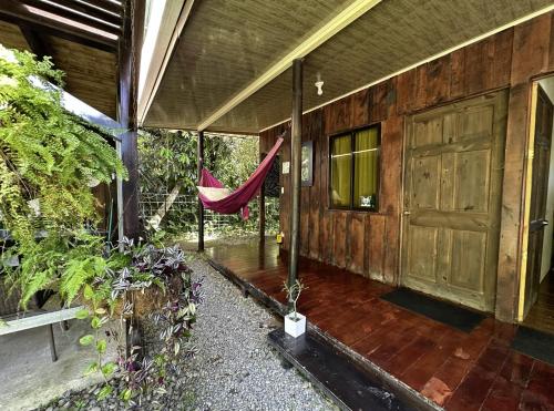 un porche de una casa con una puerta de madera y una hamaca en Casa Morpho Uvita Guesthouse, en Uvita