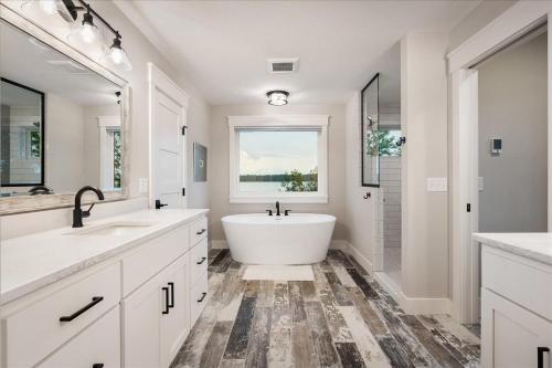 baño blanco con bañera y ventana en New! Northwoods Luxury - 5 Pines On Trout Lake, en Pine River