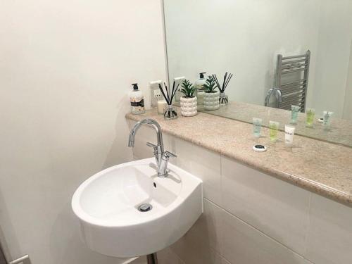 Baño blanco con lavabo y espejo en Free Parking 1 bedroom flat with double Sofa Bed, en Mánchester
