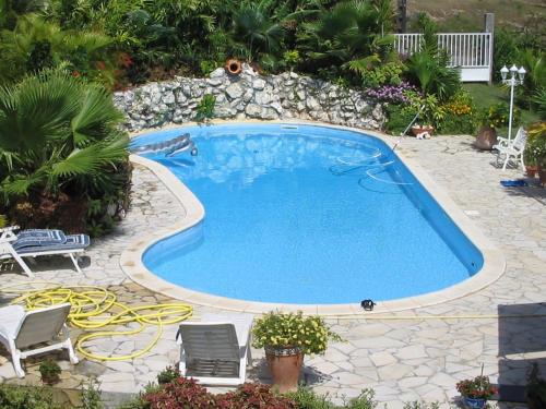 uma grande piscina num quintal com uma parede de pedra em Kote mer em Sainte-Anne