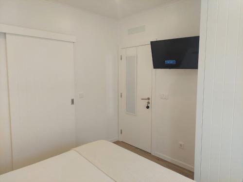 una camera da letto con un letto e una TV a parete di Lagoa azul guest house II a Vila Nova de Milfontes