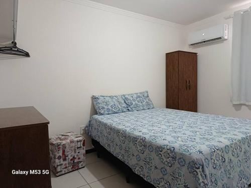 Schlafzimmer mit einem Bett mit blauer Decke in der Unterkunft Apartamento 2 quartos na área central perto do GV Shopping in Governador Valadares
