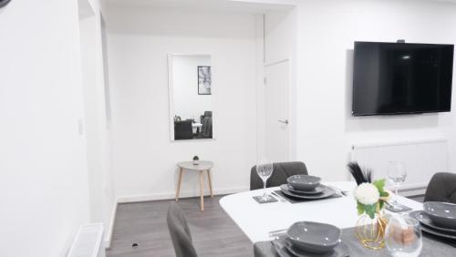 a dining room with a table and chairs and a tv at Modernized Three Bedroom House near City Stadium, Attractions, City Centre - Sky n Netflix - Convenient Transport in Manchester