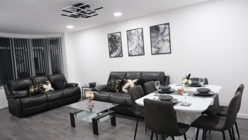 a living room with a black couch and a table at Modernized Three Bedroom House near City Stadium, Attractions, City Centre - Sky n Netflix - Convenient Transport in Manchester