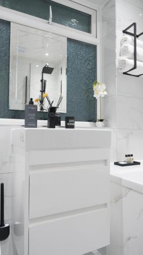 a white counter with a mirror and a vase of flowers at Modernized Three Bedroom House near City Stadium, Attractions, City Centre - Sky n Netflix - Convenient Transport in Manchester
