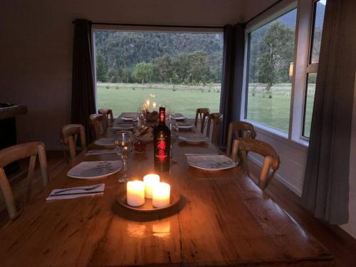 una larga mesa de madera con velas y una gran ventana en Casa de campo sobre el rio, en llifen