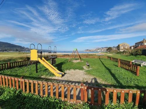 a playground with a yellow slide in a field at El rinconcito de Aldán in Aldán