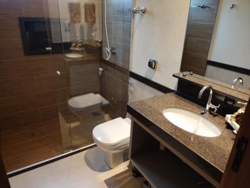 a bathroom with a toilet and a sink and a shower at Suíte Alto Padrão in Uberaba