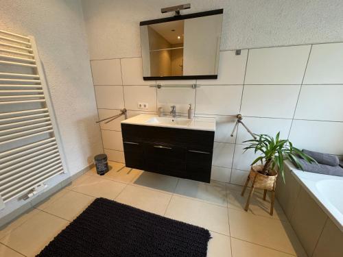 ein Badezimmer mit einem Waschbecken, einem Spiegel und einer Pflanze in der Unterkunft Fewo BOHO mit eigenem Garten nähe Salzburg in Freilassing