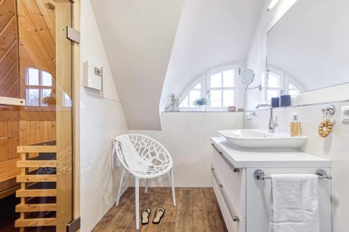 a white bathroom with a sink and a chair at Ferienhaus Haubenlerche 27 in Fuhlendorf