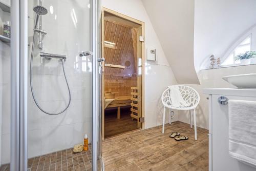 a bathroom with a shower and a sink and a chair at Ferienhaus Haubenlerche 27 in Fuhlendorf