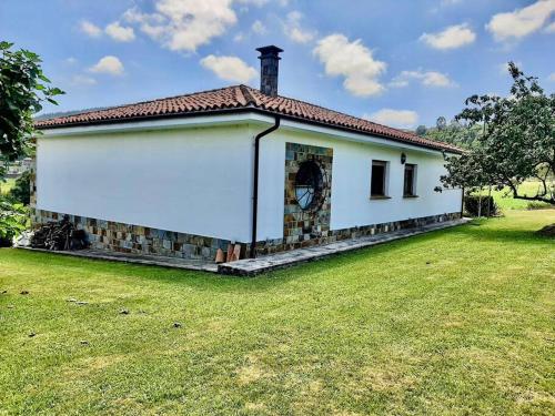 een klein wit huis met een grasveld bij Casa Margarita in Cudillero