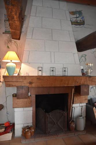 - un salon avec une cheminée en briques et une lampe dans l'établissement La maison de Typère, à Candes-Saint-Martin