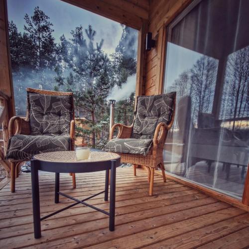 a porch with two chairs and a table on a deck at Miško kraštas in Vileikiai