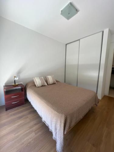 um quarto com uma cama e piso em madeira em Departamento amoblado 1 dormitorio Familiar em Bahía Blanca