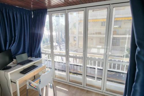 a room with a desk with a computer and a window at Apartamento primera línea de mar - cerca de Portaventura in Salou