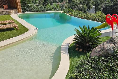 - une piscine avec un banc et une paire rouge de produits dans l'établissement villas-majos : Magnifique villa vue mer à 3 minutes des plages, à Sainte-Lucie de Porto-Vecchio